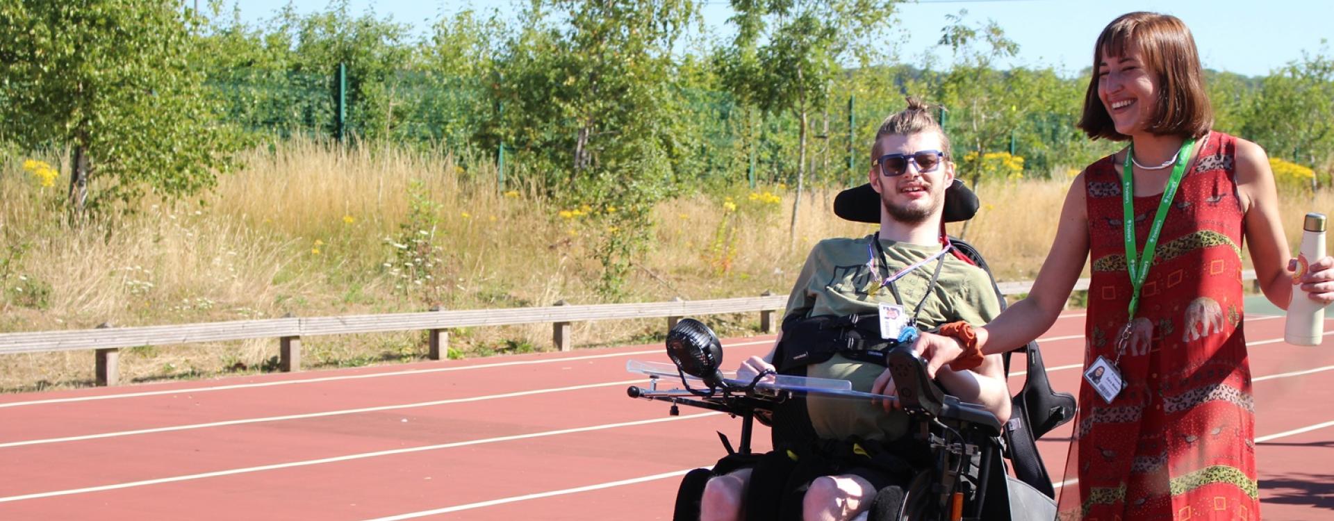 Treloar College student on a sports track with his teacher by his side on a bright summer day.