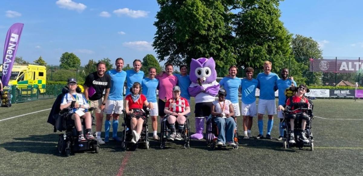 A group photo of students with Exclusive Networks members on the football pitch on a warm, sunny day.