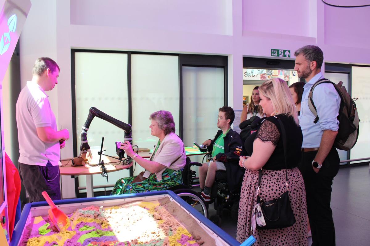A robotic arm being demonstrated to donors; on our the donors is using the robotic arm.