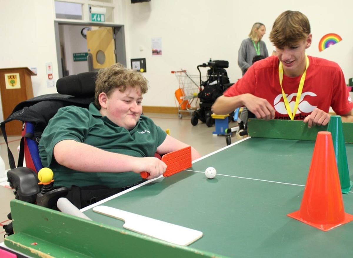 Treloar's student playing Table Cricket; a student from a mainstream school is observing. they are both having fun.