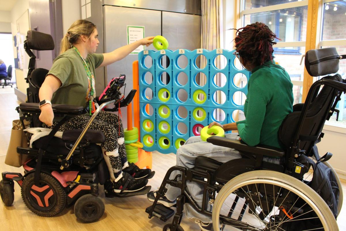 Two students using wheelchairs playing giant Connect Four together