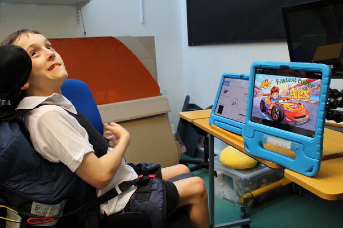 Treloar's student showcasing his digitally created book cover of racing story. The tablet is mounted on a desk.