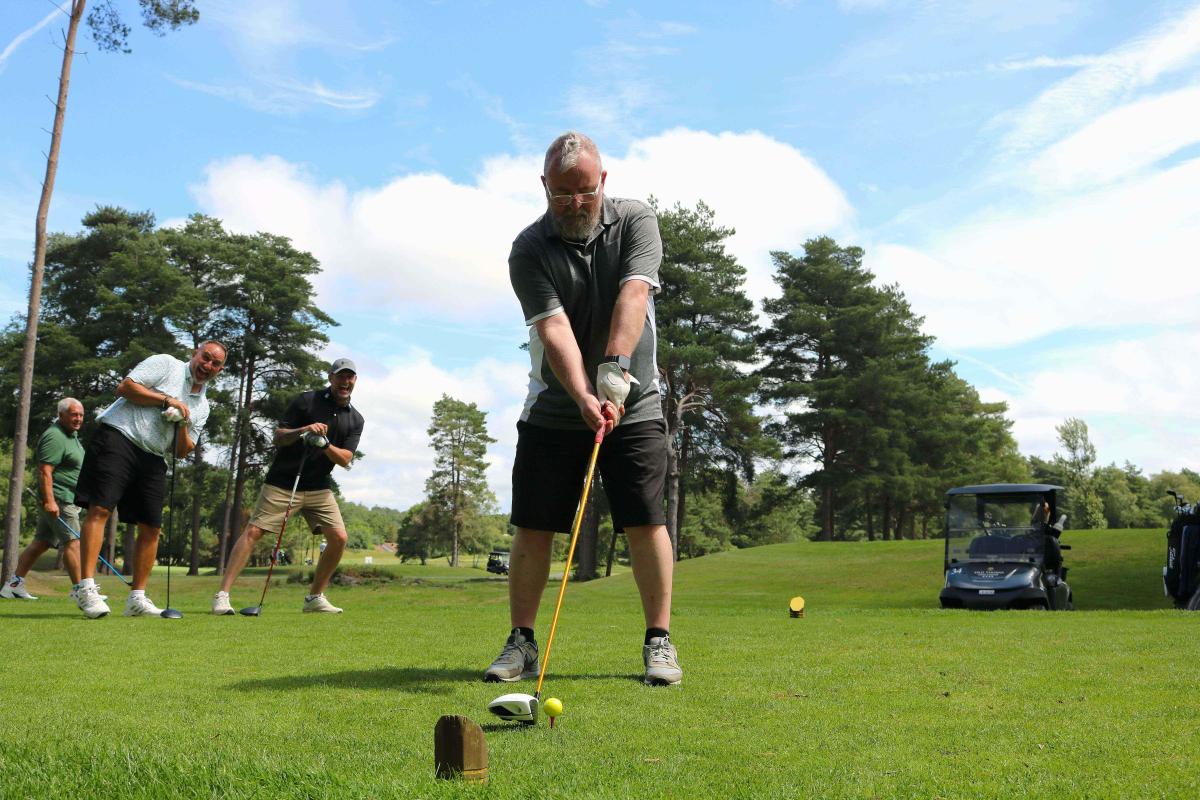 Golfer taking a shot with other team members behind