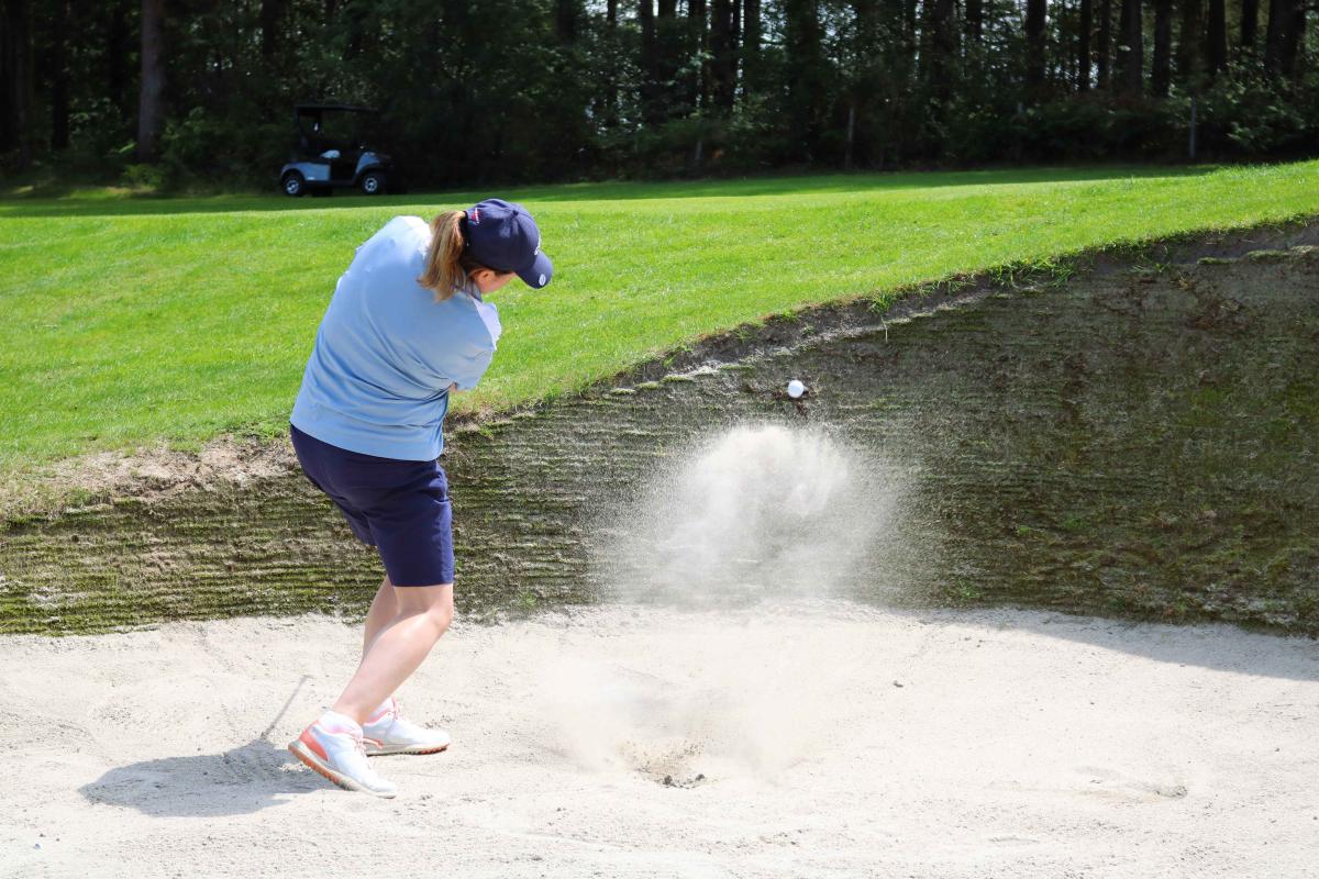 Golfer taking shot in sand 