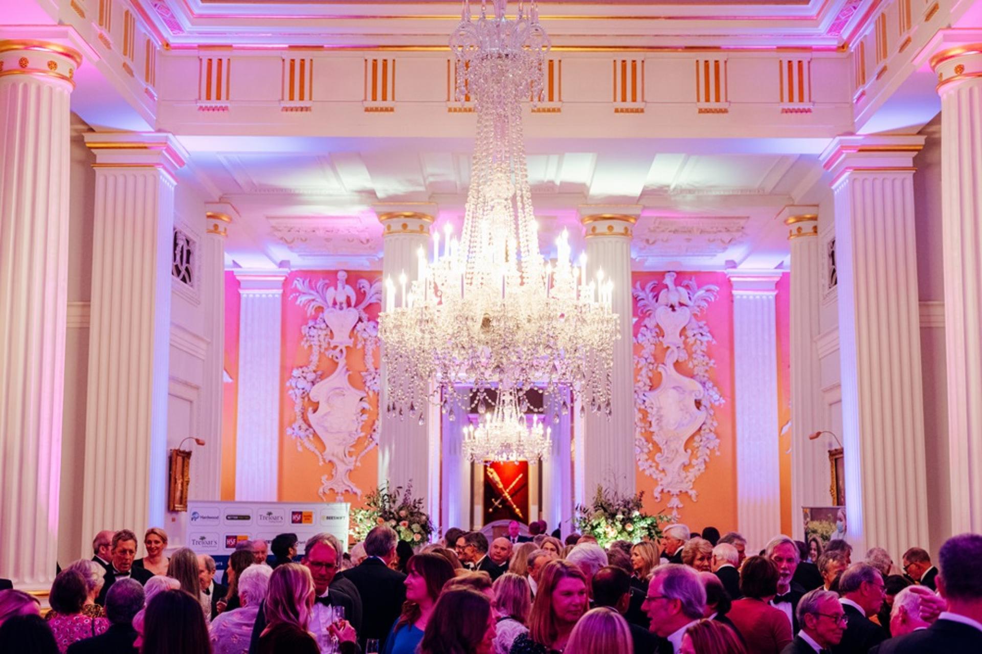 Drinks reception at Mansion House, London during The Treloar's Gala Dinner: a big crystal chandelier in the middle of the room and a lot of guests in the room drinking and chatting before the event.