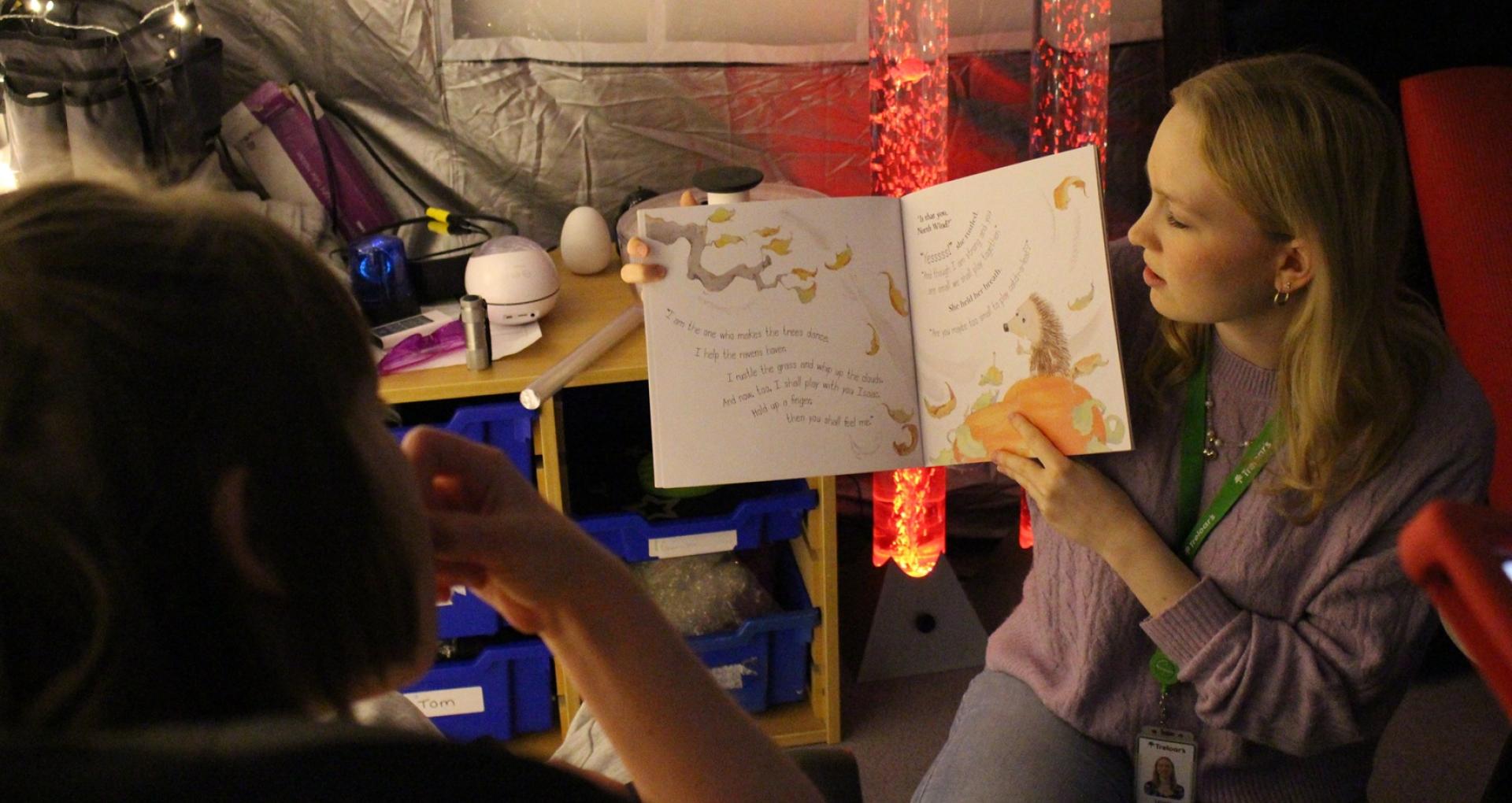 Skills for Life College class with Molly and a volunteer reading a story together with sensory mood lighting in the background