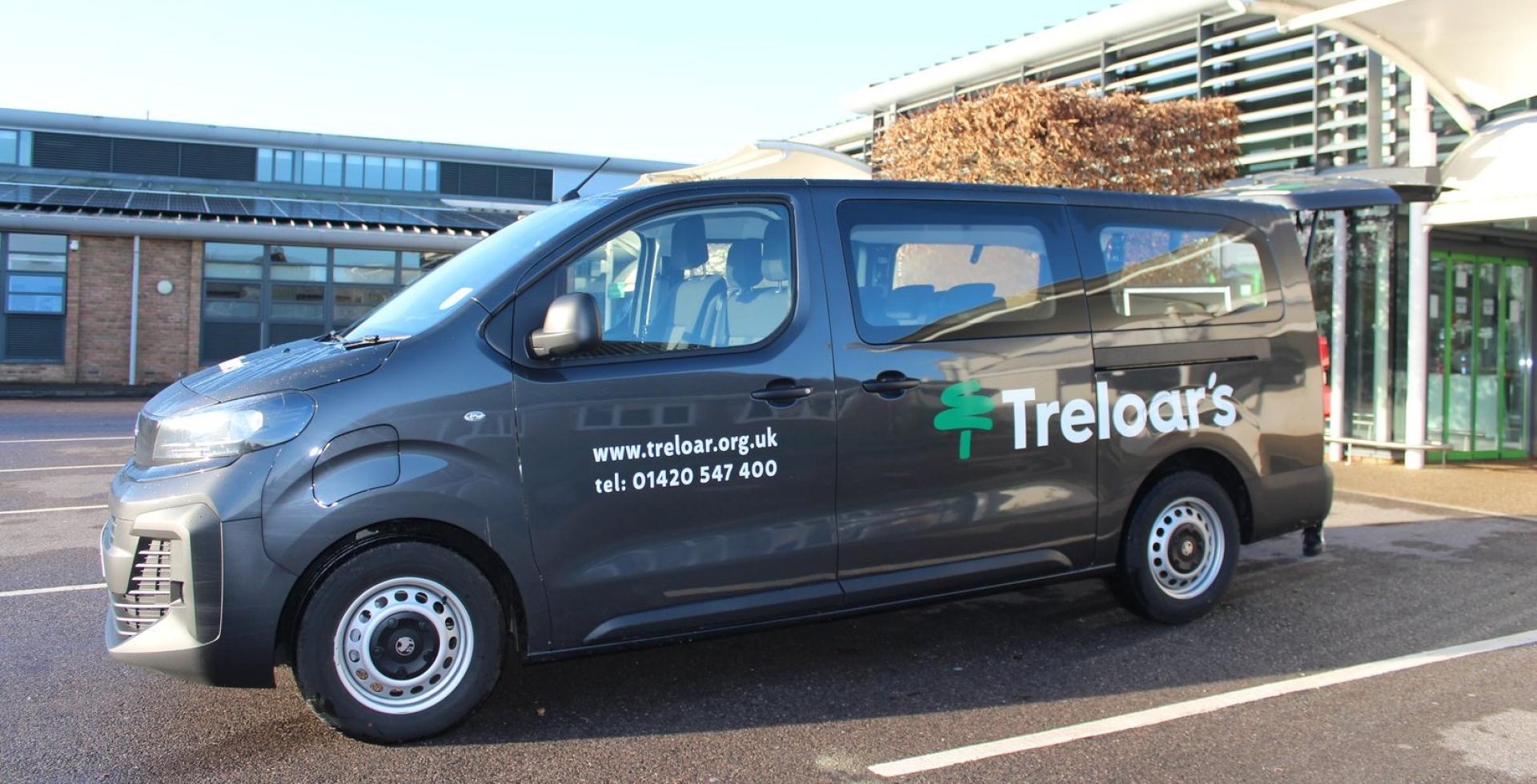 Electric minibus parked outside Treloar's main reception with blue skies above