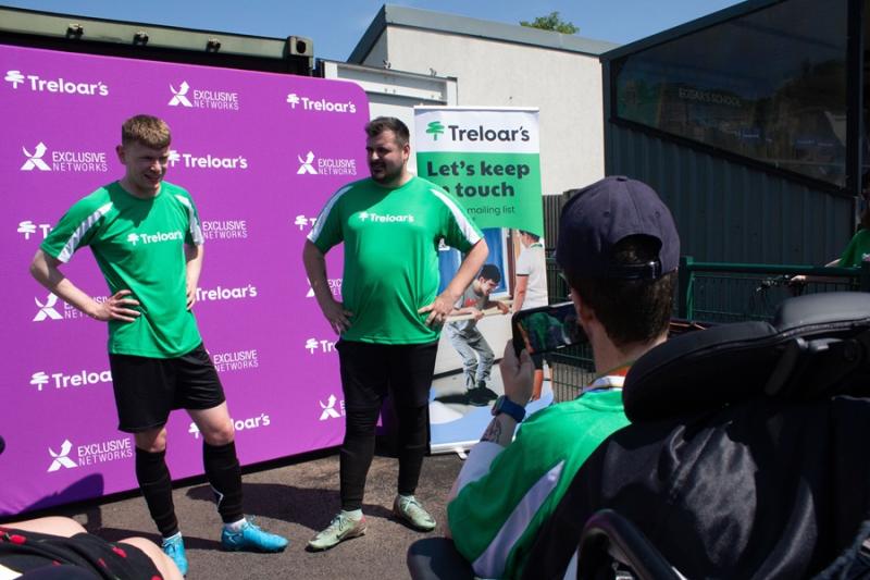 Treloar's student is conducting a pitch-side interview with 2 Treloar's staff members - both wearing green, branded Treloar's T-shirts.