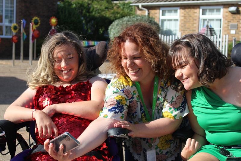 Treloar College students with their student support assistant taking a selfie: the assistant is holding the phone. They are all laughing and looking into the camera.