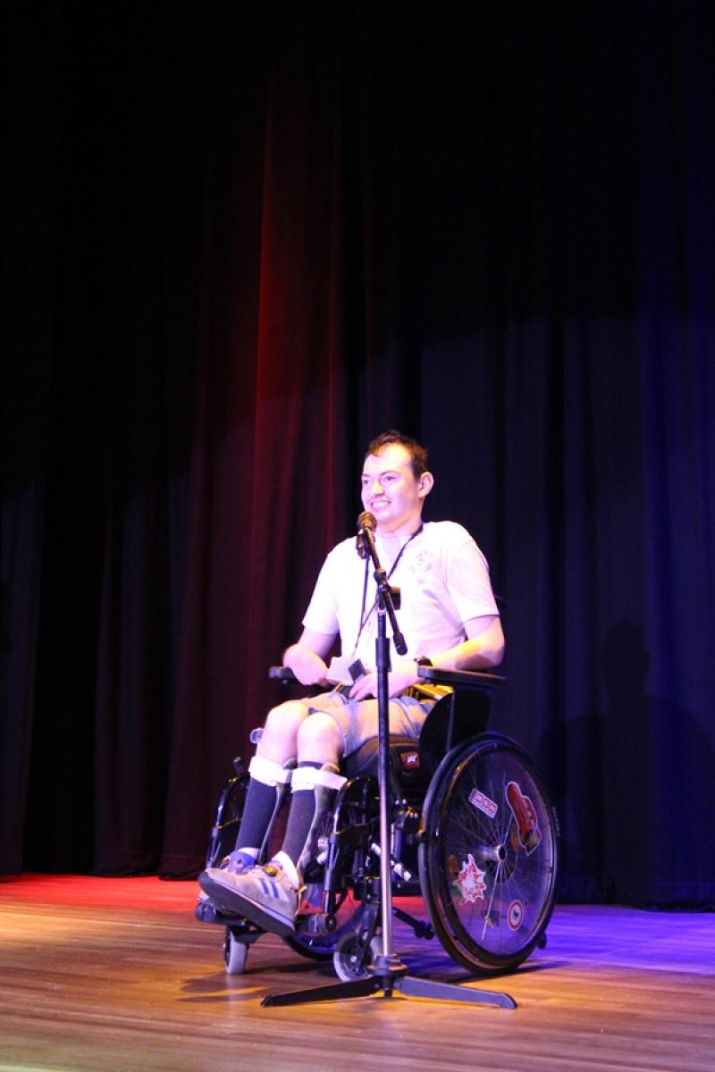 Treloar College student performing on the stage during Treloar's Got Talent competition. The stage is lit up with colourful lights.