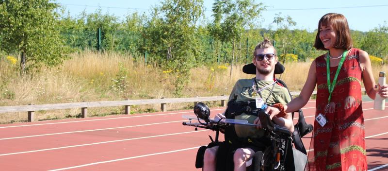 Treloar College student on a sports track with his teacher by his side on a bright summer day.