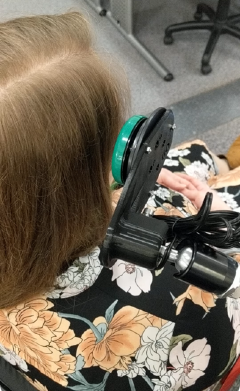 An over the shoulder close-up of a person sitting in the wheelchair demonstrating how Treloar's students using head switch.