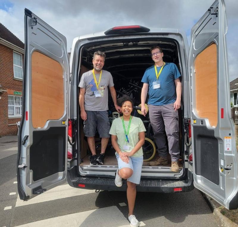 Treloar's staff member with 2 men, all wearing lanyards stand and sit at the open back of a white van under a cloudy sky.