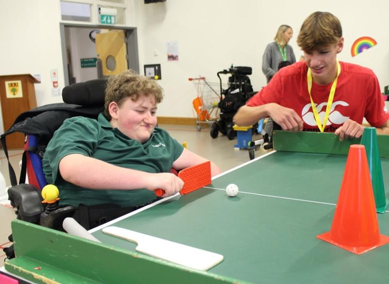 Treloar's student playing Table Cricket; a student from a mainstream school is observing. they are both having fun.
