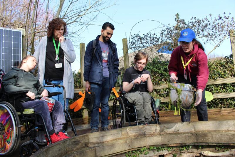 A group of students pond dipping with a visitor from Deadwater Rangers