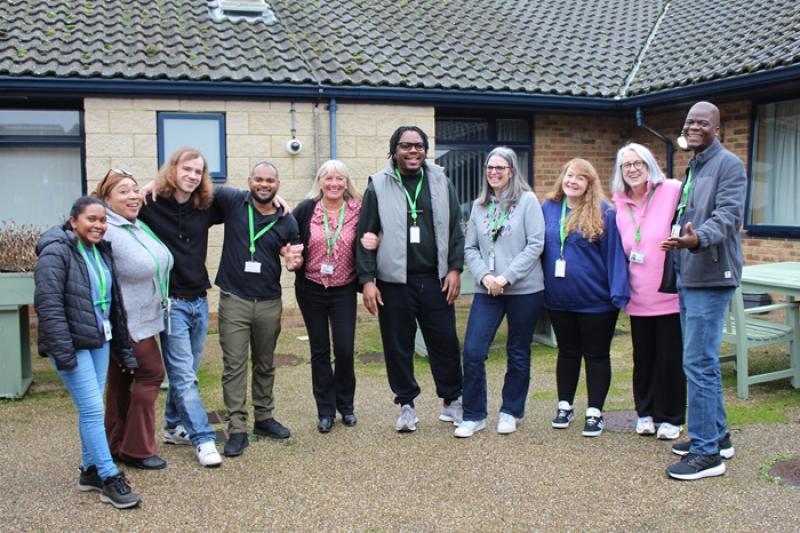 Group of ten Treloar's house staff standing outside one of the residential houses, smiling and posing together on a paved area.