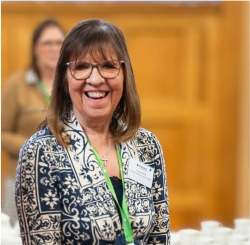 Photo of Cheryl Brewer Chair of Trustees Treloar Trust, she is wearing a blazer and a green lanyard, smiling towards the camera