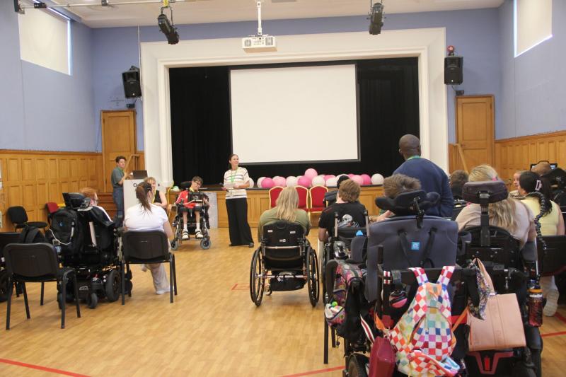Students in wheelchairs, in a school hall listening to a speaker, giving Q&A session