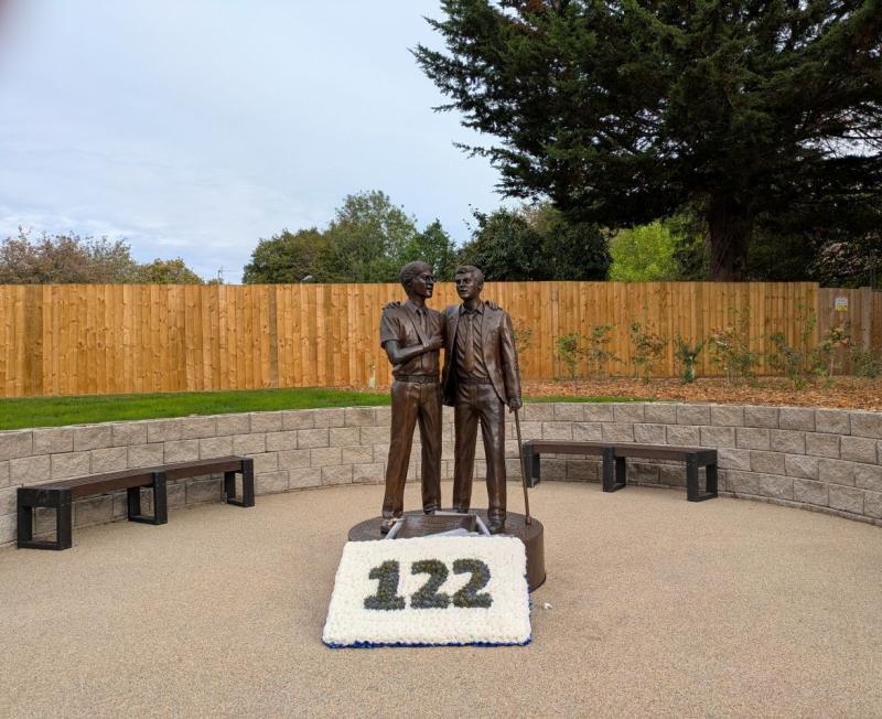 Treloar's Memorial to students affected by infected blood, a bronze statue of two boys, with a floral tribute at the base, in memory of the students who died following the treatment they received.