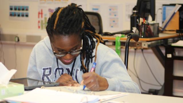 Treloar's student at her desk making notes.