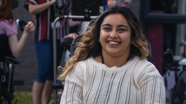 Treloar College Amirah, smiles at the camera, wearing a cream jumper