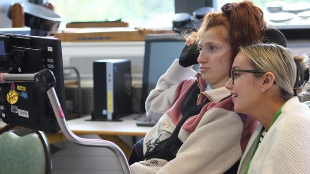 Treloar College student looking at her iPad in front of her; her assistant is sitting next to her and is also looking at the screen. They are both focused.