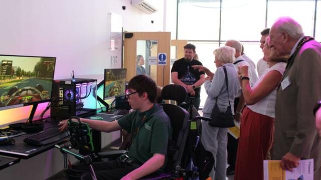 Treloar's student demonstrating the eSports to donors: he is playing a computer games, while donors are watching and discuss the growing sector of eSports