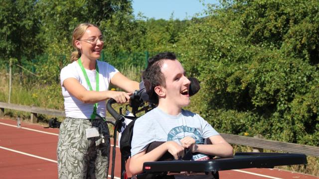 Treloar College student is on a race track and his assistant is right behind him pushing the wheelchair.