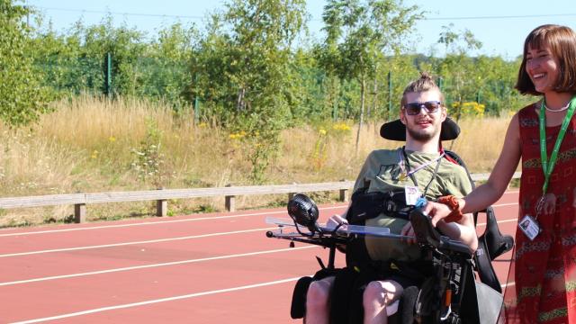 Treloar College student on a sports track with his teacher by his side on a bright summer day.