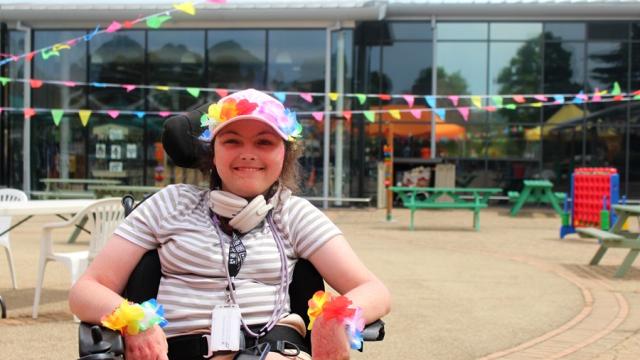 Treloar College student wearing a striped shirt and colorful flower accessories at an outdoor event with festive bunting overhead.