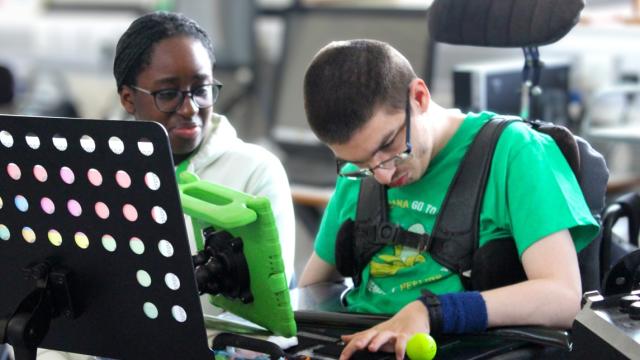Treloar's volunteer supporting a student during College Orchestra practice