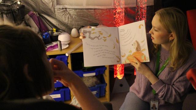 Skills for Life College class with Molly and a volunteer reading a story together with sensory mood lighting in the background