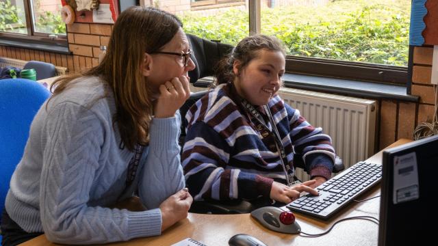 Treloar College student working with a support assistant, seated by a window at HSDC Alton College