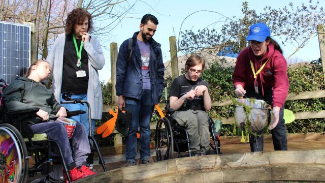 A group of students pond dipping with a visitor from Deadwater Rangers