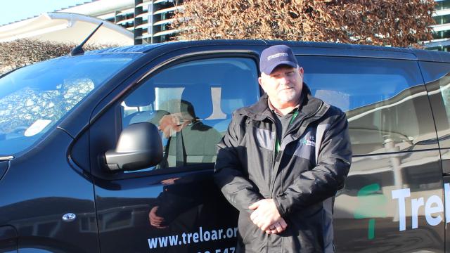 Treloar's driver Mark stands in front of a Treloar's branded minivan