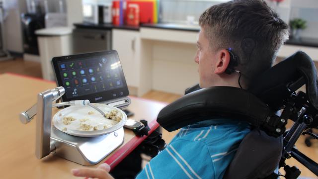 Student using eye gaze control via an AAC to operate a neater eater adaptable feeding system