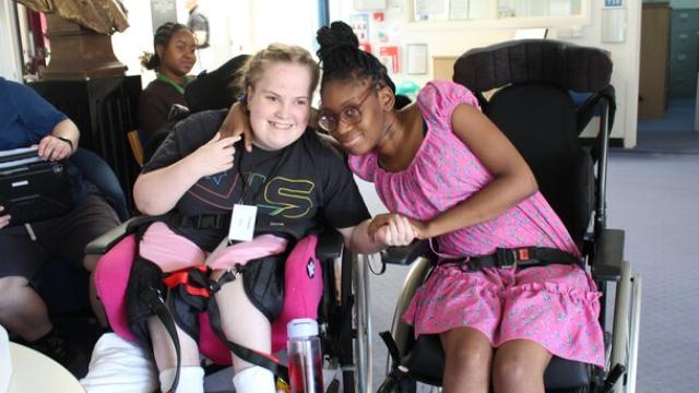Two female students in wheelchairs smiling together