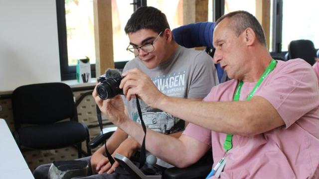 College student learning to use a camera with a support assistant