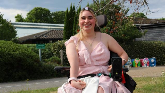 Treloar's student in a pink dress smiling while posing for pictures outdoors on a sunny and warm day.