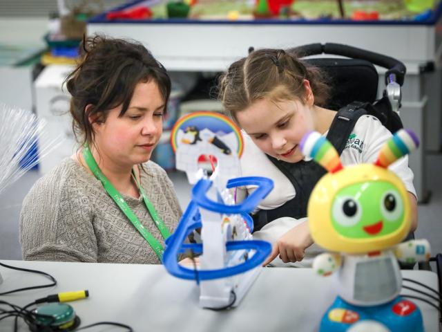 Member of staff with young child looking at interactive toys