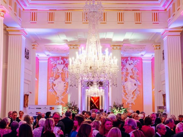 Drinks reception at Mansion House, London during The Treloar's Gala Dinner: a big crystal chandelier in the middle of the room and a lot of guests in the room drinking and chatting before the event.