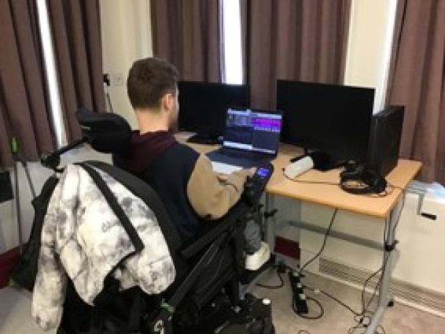 Joe at the desk working on his music using a laptop.