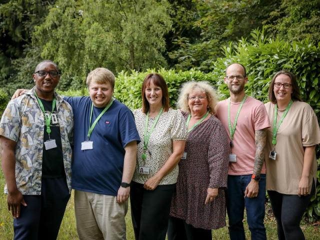 A group shot of Treloar's employees outdoors: a green lawn and shrubs in the background.