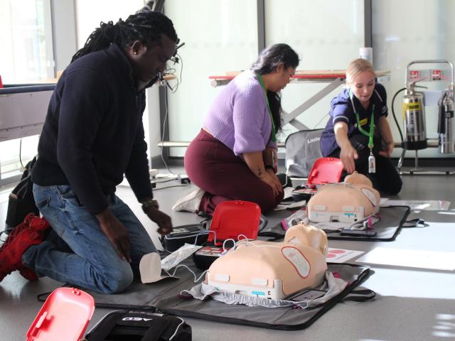 Two Treloar's staff taking part in basic life saving training, directed by a nurse