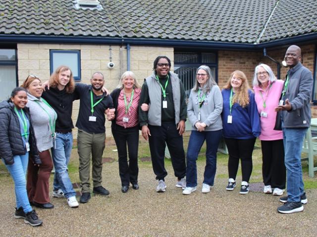Group of ten Treloar's house staff standing outside one of the residential houses, smiling and posing together on a paved area.