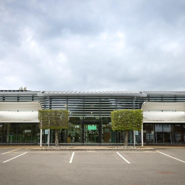 The front of Treloar's main building - empty parking spots in front of it and a cloudy sky above the building.