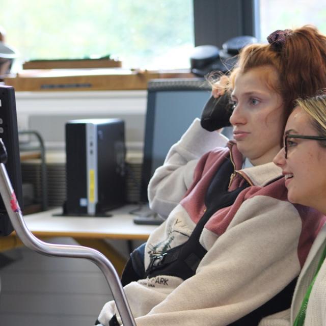 Treloar College student looking at her iPad in front of her; her assistant is sitting next to her and is also looking at the screen. They are both focused.