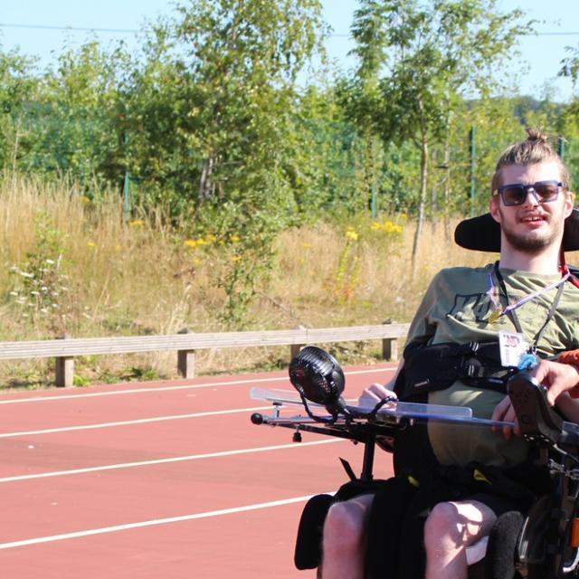 Treloar College student on a sports track with his teacher by his side on a bright summer day.