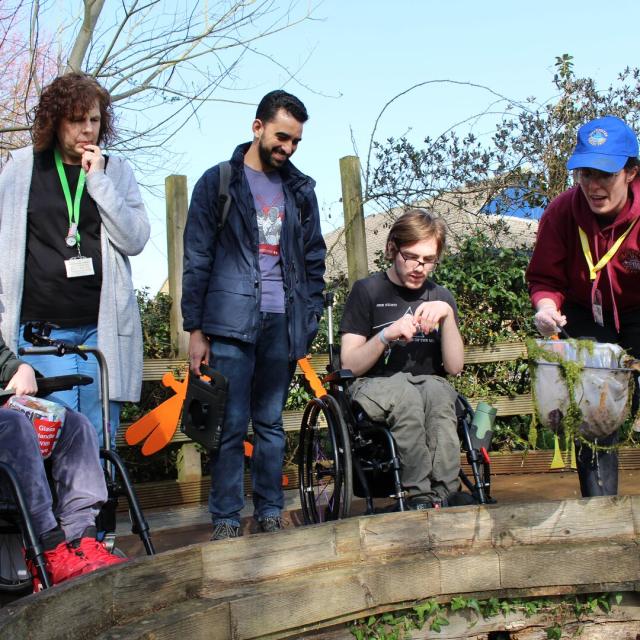 A group of students pond dipping with a visitor from Deadwater Rangers