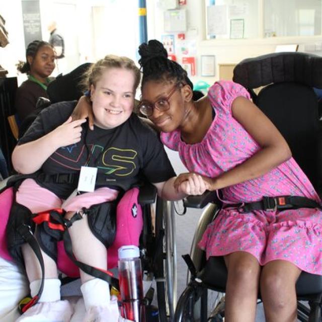 Two female students in wheelchairs smiling together